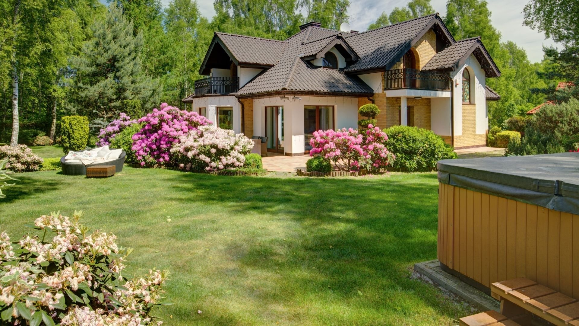 Well-maintained house with lush lawn, pink flowers, and professional landscaping care