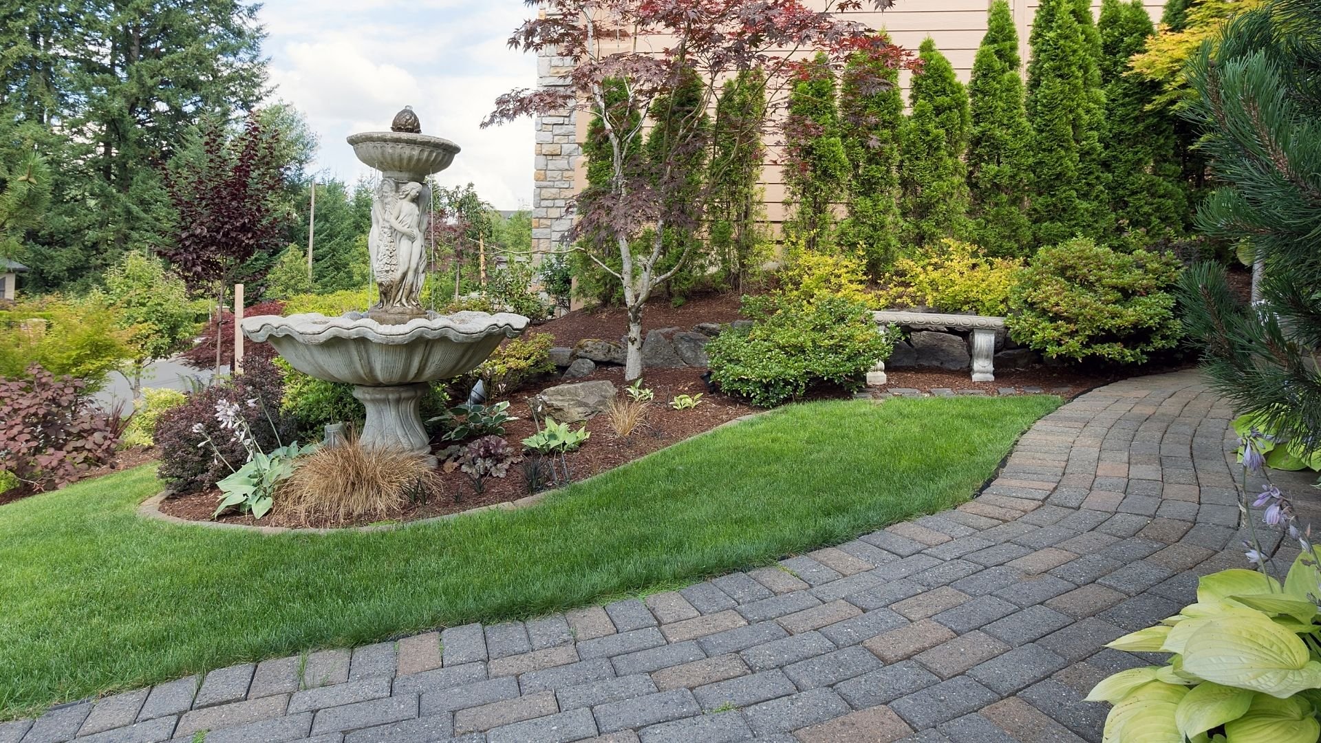 Manicured garden with stone fountain, curved lawn, and carefully maintained landscaping
