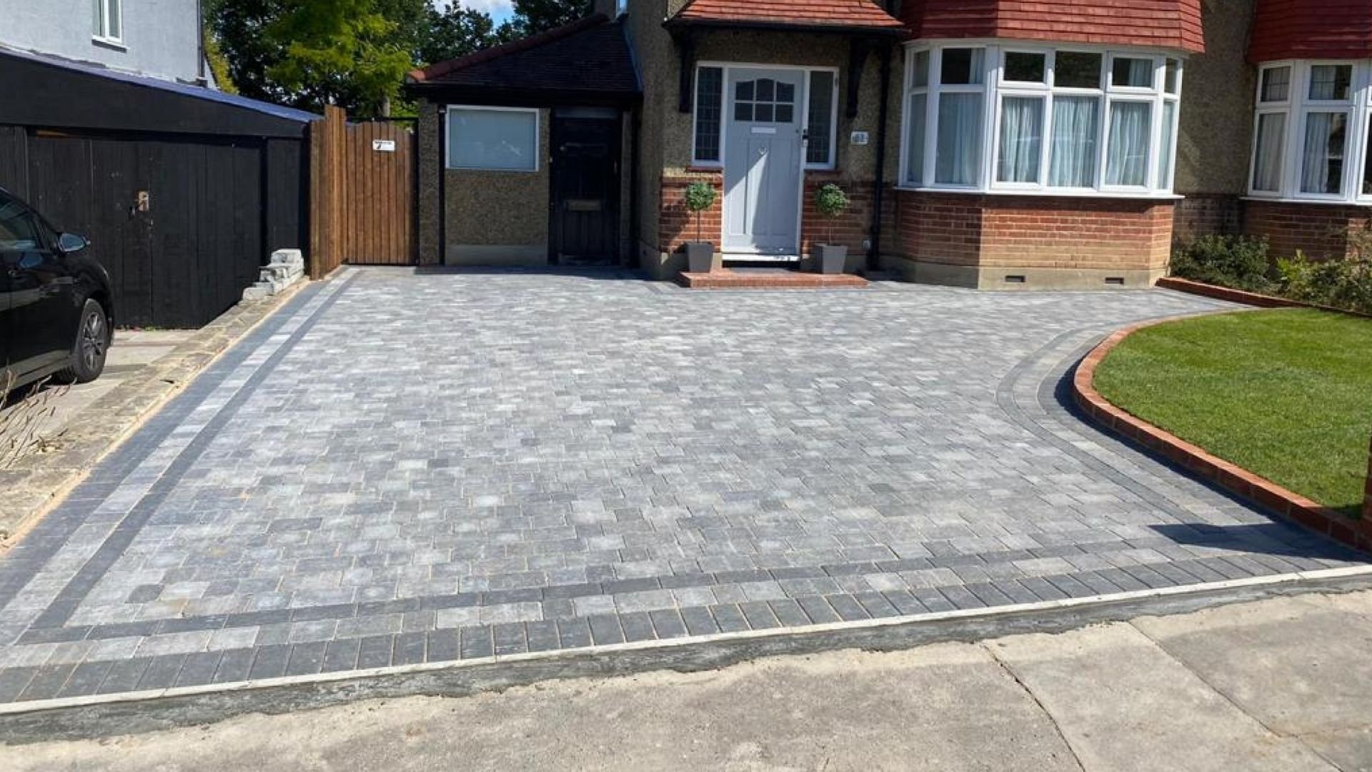 Newly paved driveway with well-maintained lawn and modern home exterior